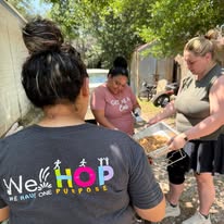 A volunteer in a WeHOP shirt serving food outdoors