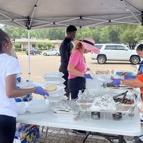 Volunteers preparing community meals under a canopy